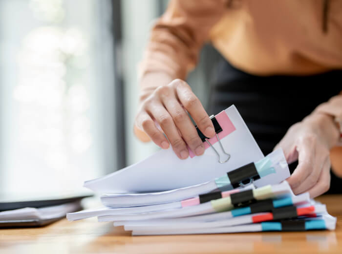 Person sorting a large pile of papers with lots of individual colourful clips.