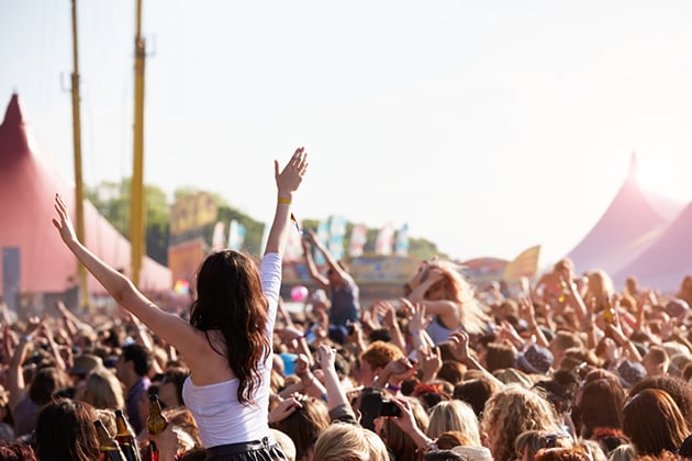 Crowd at a festival, with tents and flags in the background.