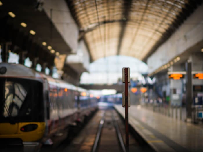 A train stands blurred in a train station with bright light and no visible passengers on the platform