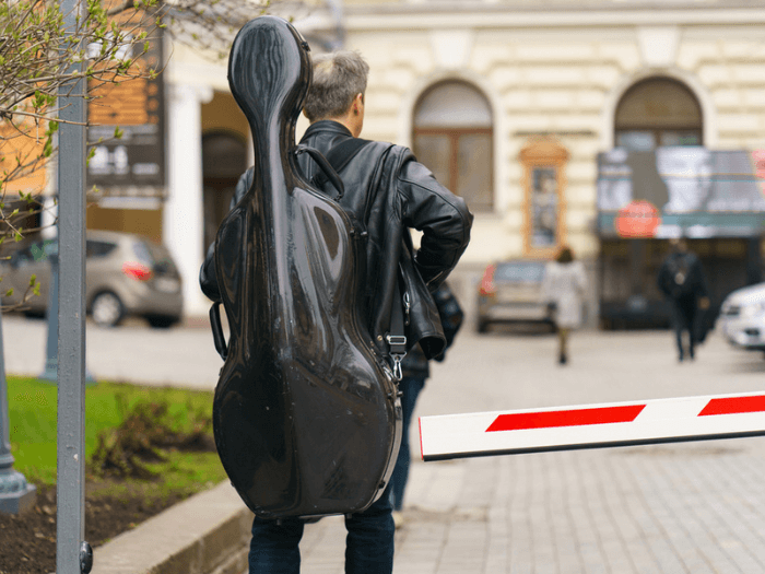Person walking into a venue with a cello case on their back.