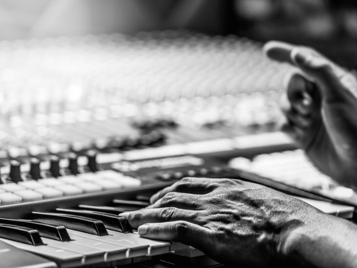 Closeup of a composer playing a midi keyboard.