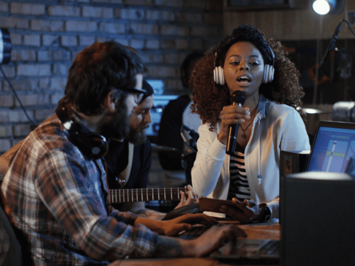Young musicians recording in home studio, singing and playing guitar.